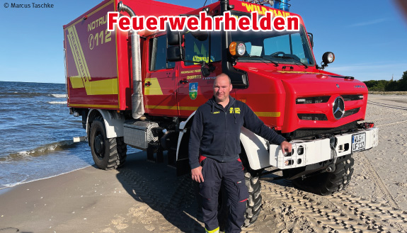 Roter Unimog der Feuerwehr Ückeritz steht am Strand. Davor steht ein Feuerwehrmann.