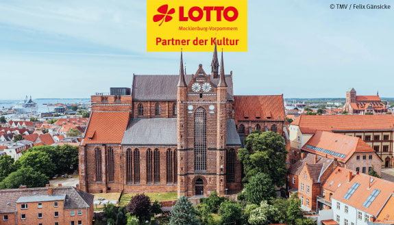 Backsteinkirche St.-Georgen umgeben von zahlreichen Gebäuden in der Wismarer Altstadt.