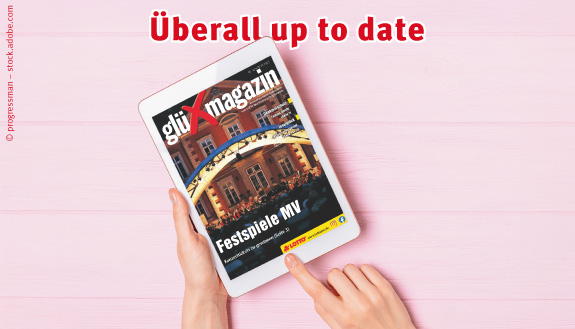 Hände halten Tablet, auf dem das glüXmagazin angezeigt wird