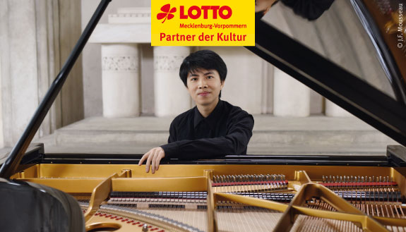 Pianist Kita Armstrong sitzt am schwarzen Klavier sowie Logo LOTTO MV - Partner der Kultur.