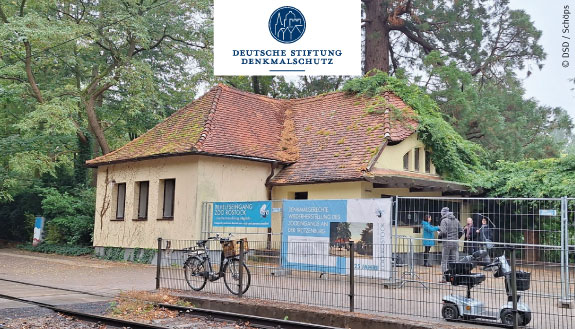 Historisches Eingangsgebäude im Zoo Rostock mit bewachsenem roten Dach.