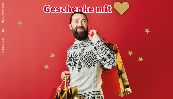 Lachender Mann mit Bart und goldenen Geschenkt&uuml;ten in den H&auml;nden