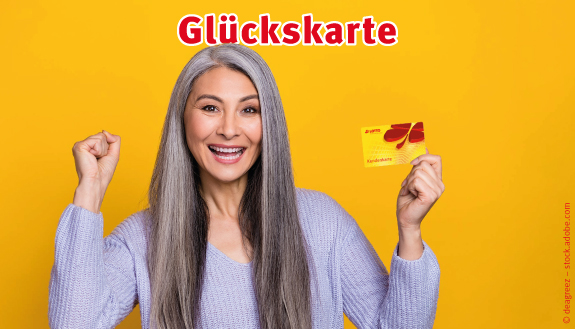 Lachende Frau vor gelbem Hintergrund macht Siegerpose und h&auml;lt Kundenkarte hoch