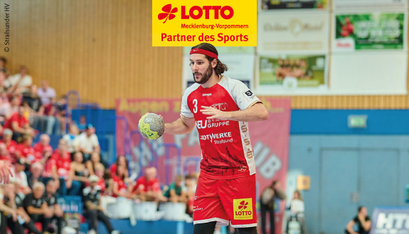 Handballer im roten Trikot am Ball