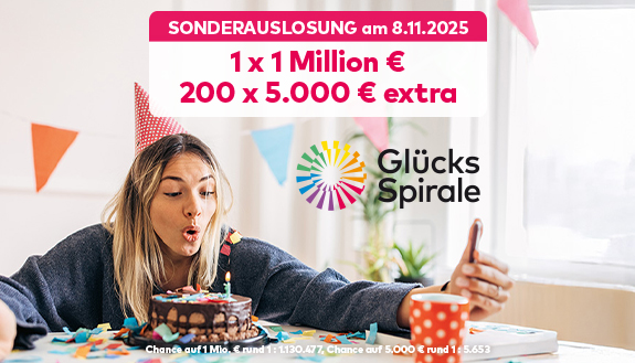 Blonde Frau mit Partyhütchen auf dem Kopf pustet Kerze auf Torte aus