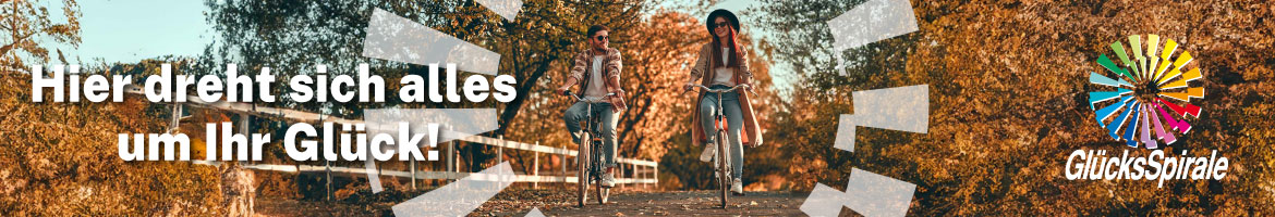 Pärchen auf Fahrrädern in Herbstlandschaft und GlücksSpirale-Logo