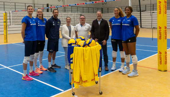 Gruppenbild von vier Volleyballerinnen und vier weiteren Personen am Netz.